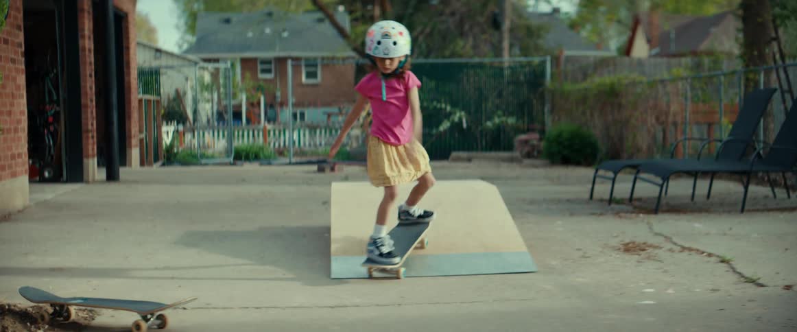 A confident young girl skateboards up a ramp and turns around with determination in her backyard