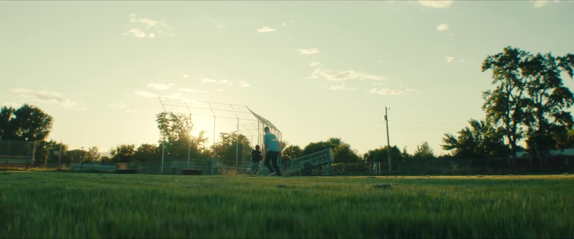 A man throws a football to a boy who catches it and tries to evade the man