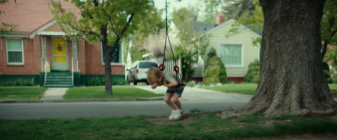 A child is playing on a swing in a neighborhood