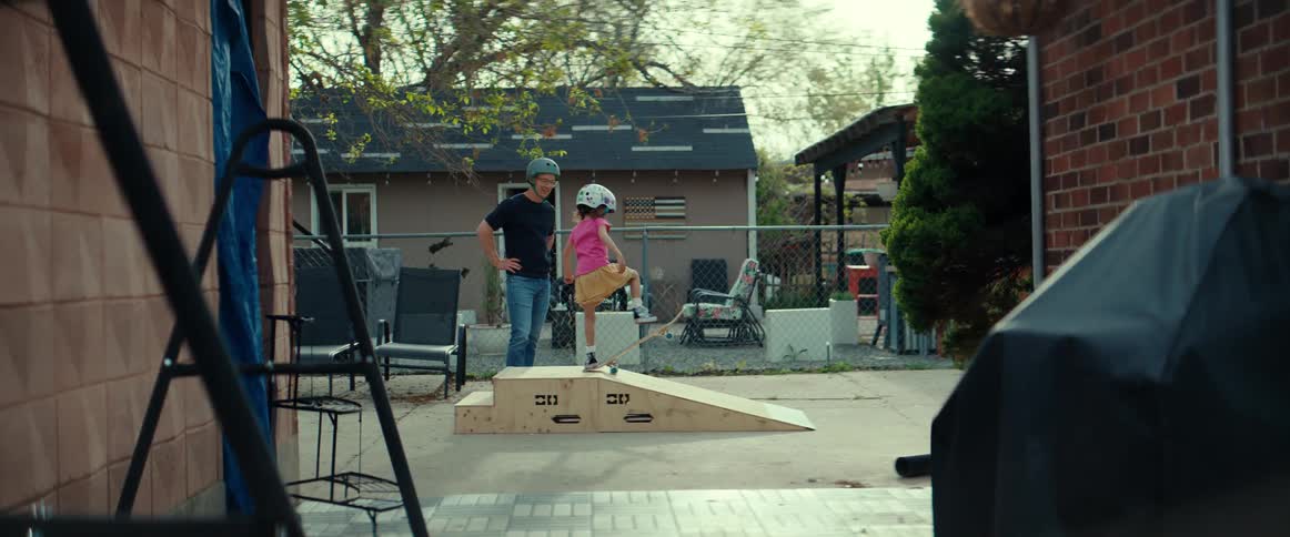 Father is teaching his daughter how to skateboard outdoors
