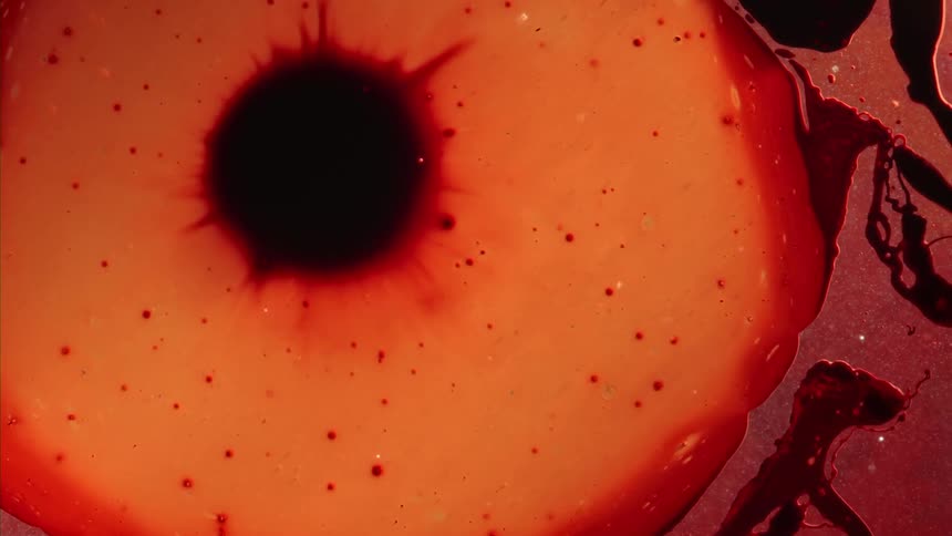 An orange cell bursts and expands on the surface with a dark nucleus breaking apart
