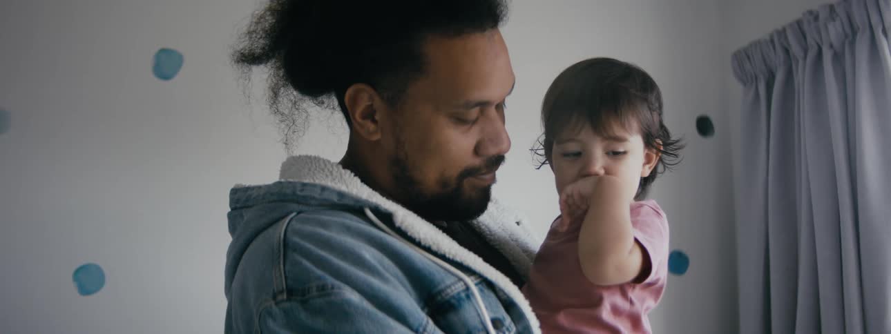 A father is holding his newborn baby indoors
