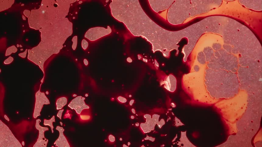 Dark red and black glob floats on liquid and spreads and disperses onto liquid