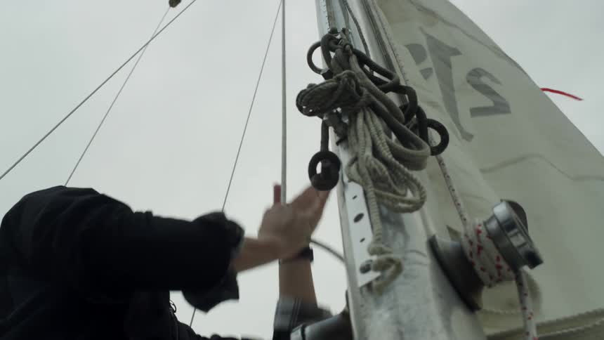 A man raises the sail on his boat