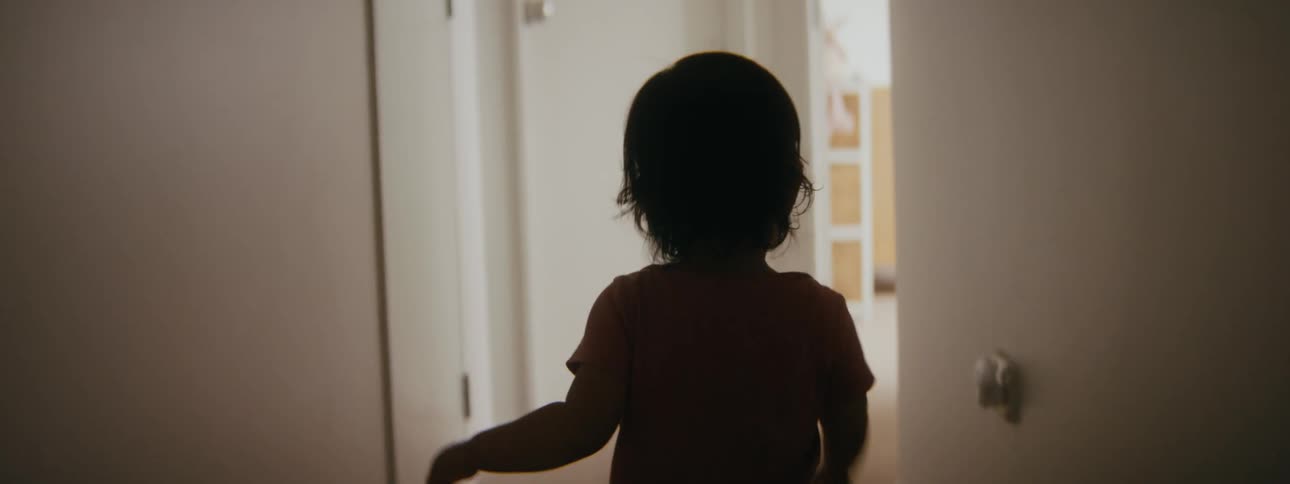 A toddler is walking through rooms in a house