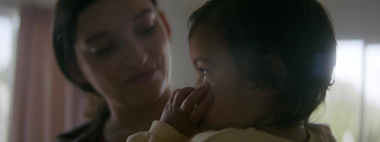 A woman holds her baby at home