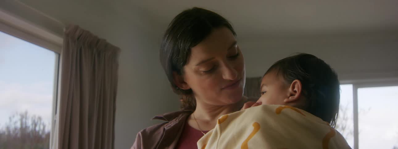 A mother is holding her newborn baby indoors