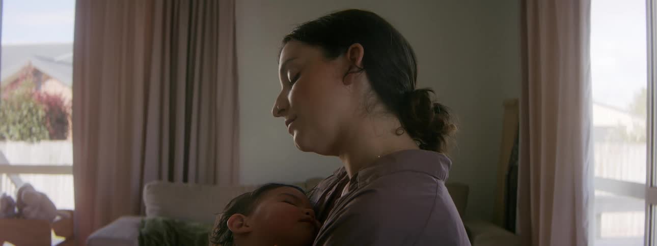 Mom gently sways as she sits holding her sleeping daughter