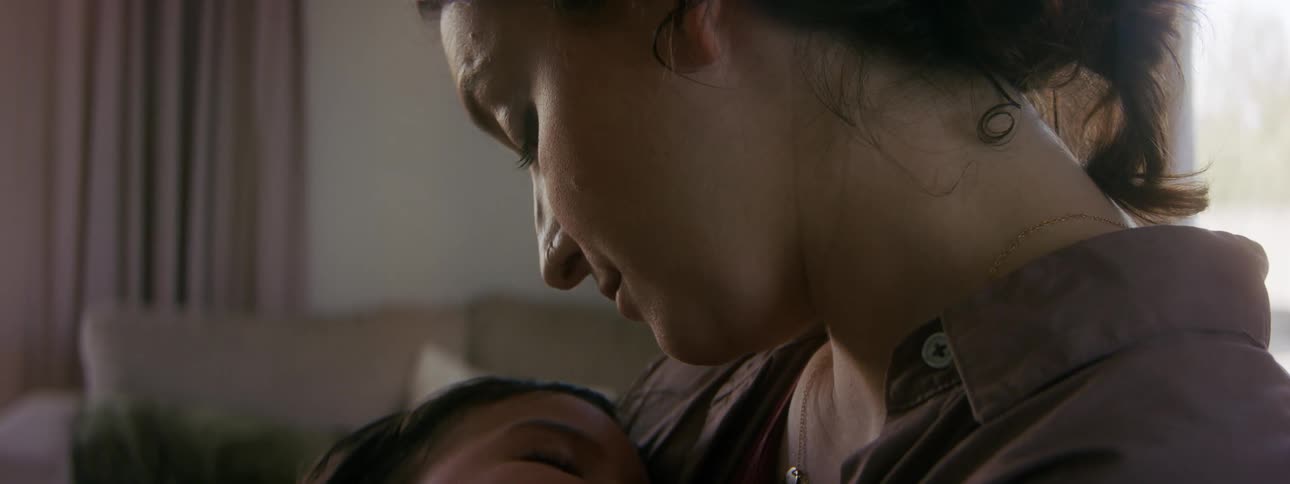 A mother is holding her newborn child indoors