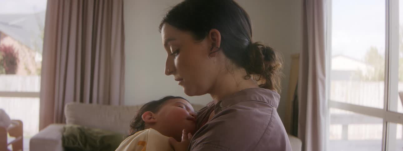 A mom sits holding her napping baby gently swaying back and forth