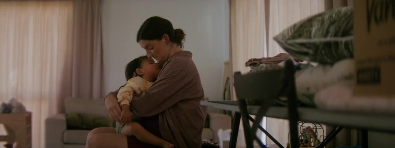 Mother playfully hugs her daughter while sitting in the living room at home