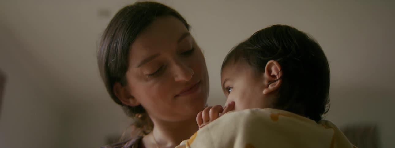 A mother is holding her child and standing in a room