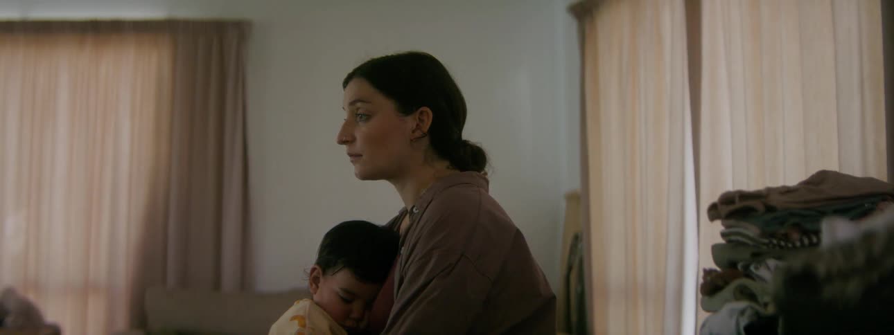 A tired mother rocking her infant to sleep at home