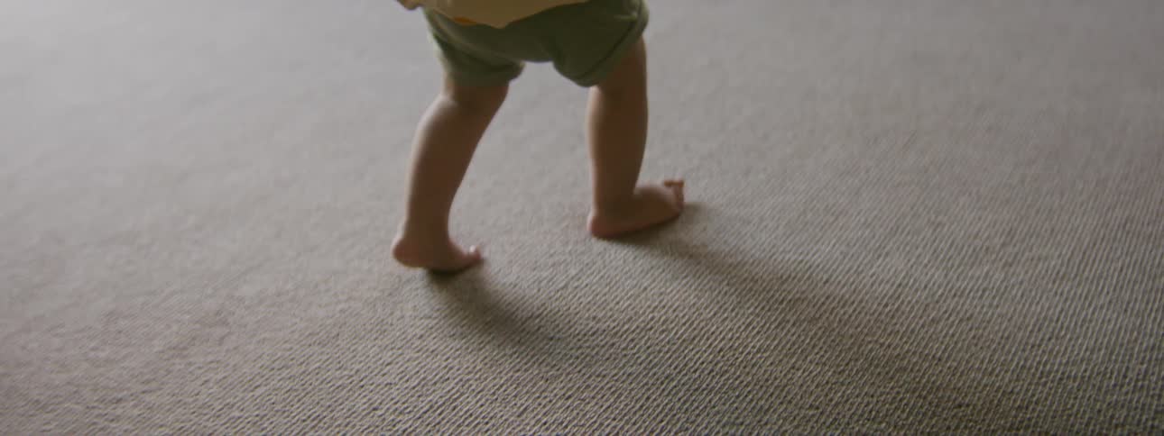 Toddler walks across pale carpet
