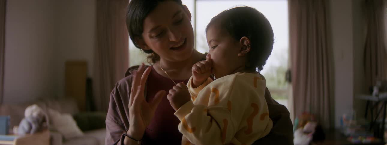 A mother is holding her daughter in her house