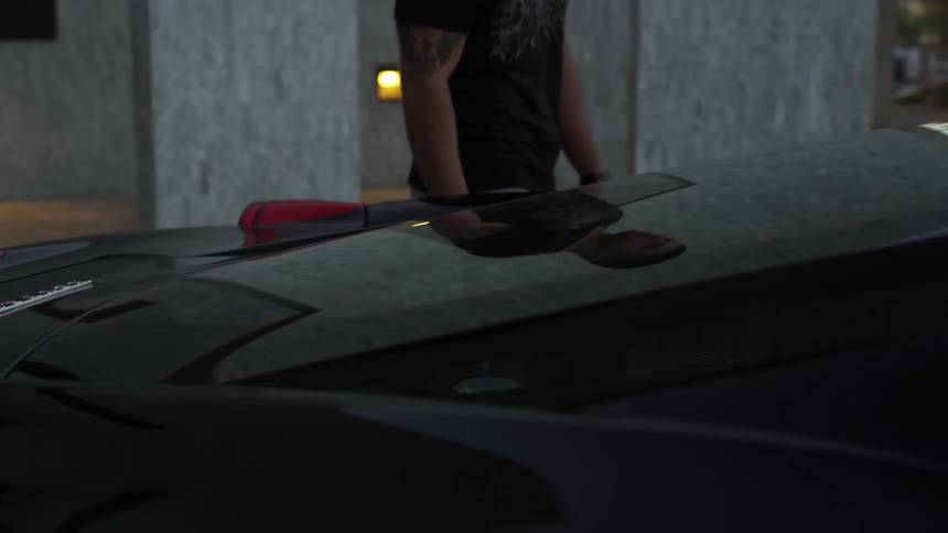 A man walks and enters a black vehicle