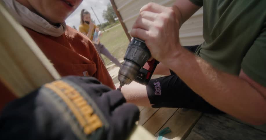 Two men are drilling as they build a ramp and a man and woman watch