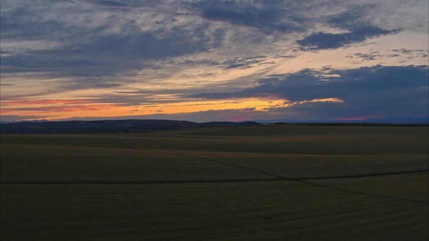 Rows of crops stretch to red sky sitting over mountain