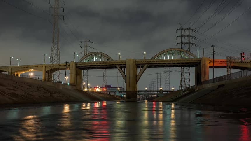 Vehicles drive on a bridge over a river at night