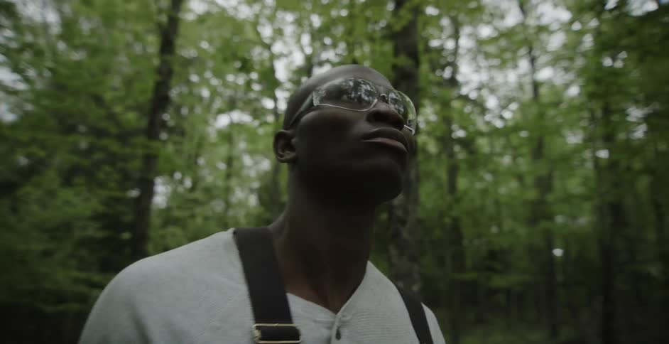 A man looks around as he stands in a forest