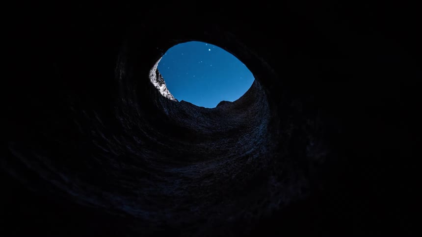 The opening of a cave shows the stars in the sky then the sun shines in
