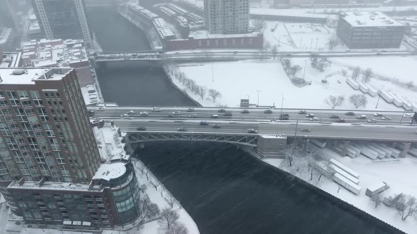 Heavy snow falls as vehicles drive over downtown Chicago bridge
