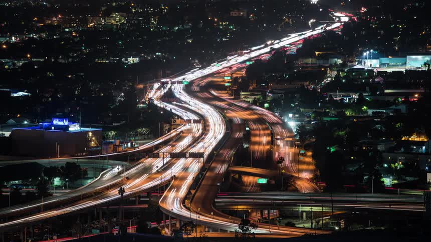 A hypserlapse shot of heavy traffic on a freeway through a metropolis at night