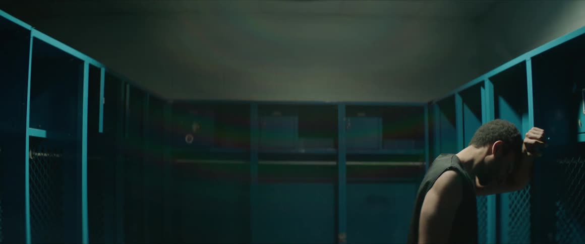 A man leans against a locker before standing straight