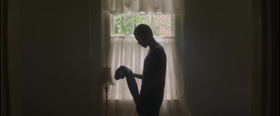 A man holding a shirt in a dim room