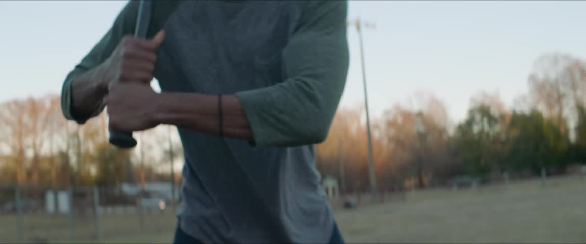 A man picks up a bat preparing to swing