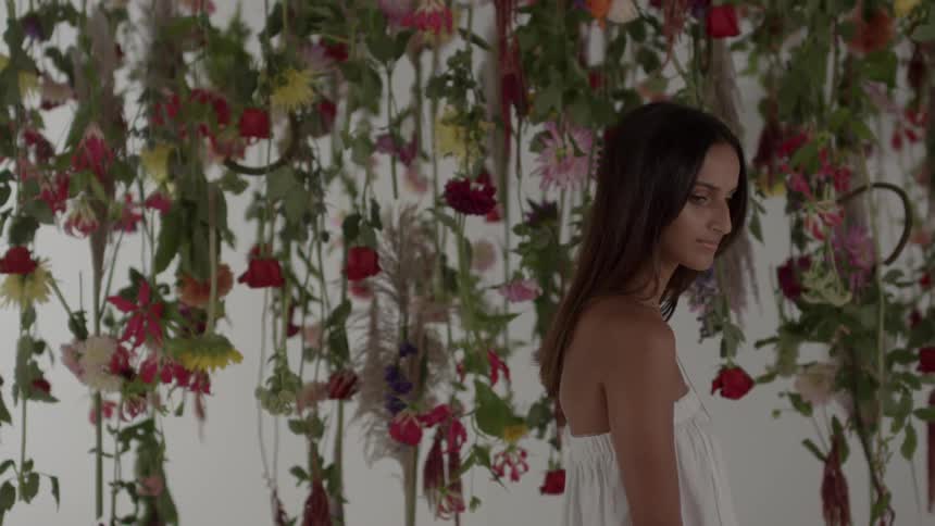 A woman stares intently near hanging flowers