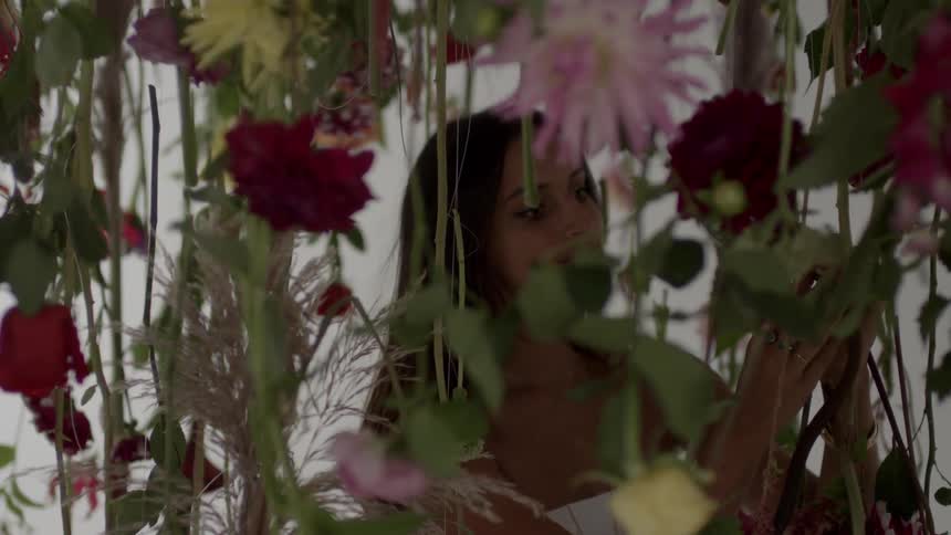 A woman ties flowers to a vine