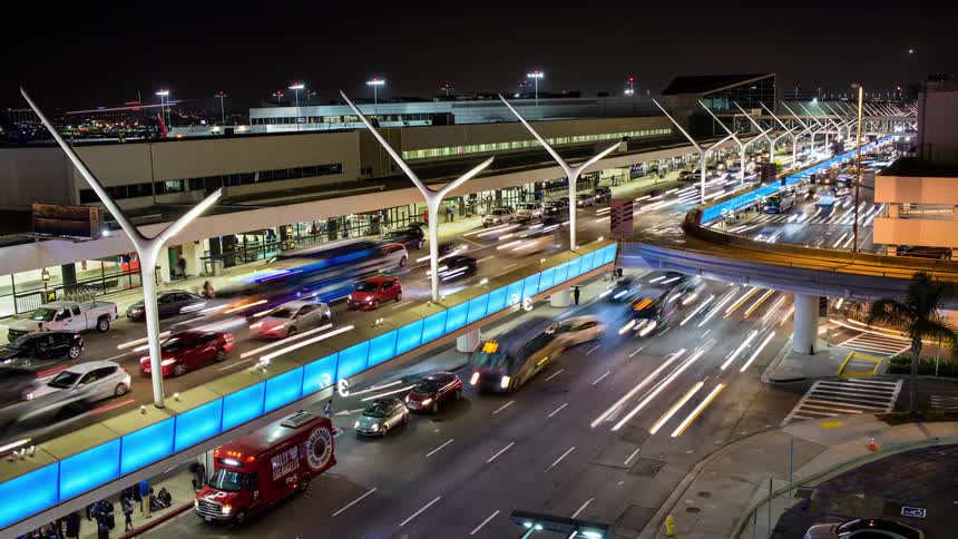 Planes land in the background as traffic moves people to and from the airport terminals