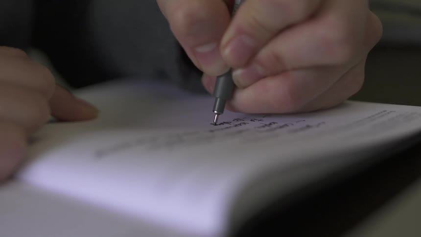 A person is writing in a notebook