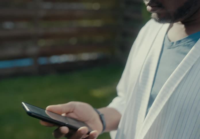 A man is standing outside scrolling through his cell phone