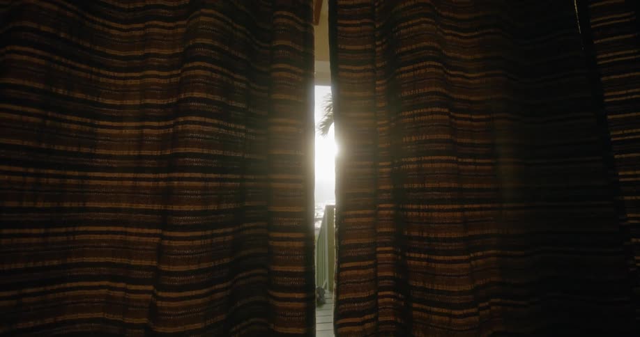 Curtains blowing in a home with the ocean showing outside the curtains