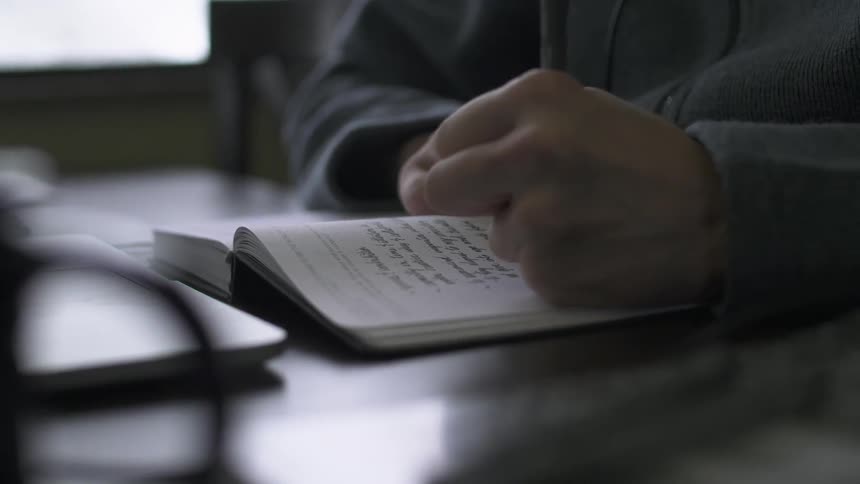 A man is writing in a notebook