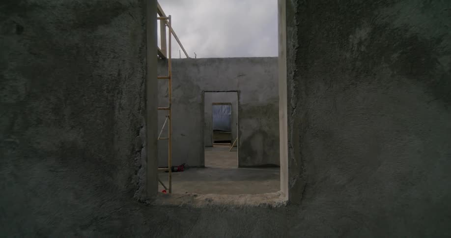 The open windows and doorways of an unfinished building with poured foundation and floor