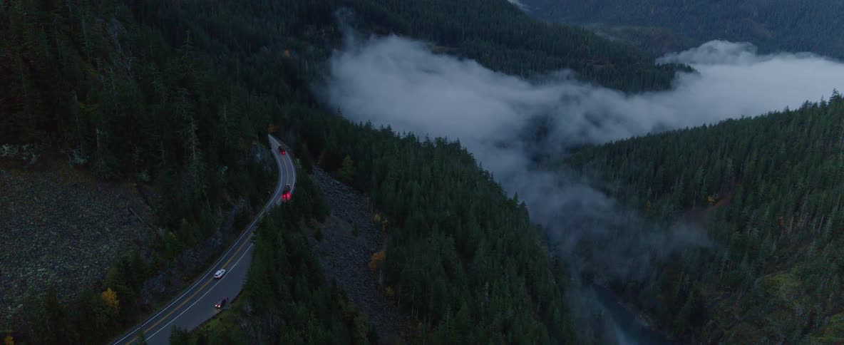 An aerial view of cars traveling on a mountain road on a cloudy night