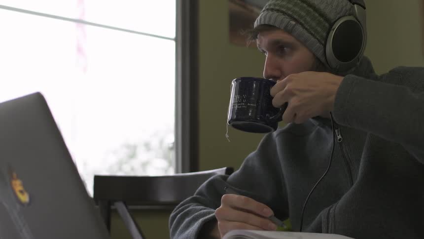A man picks up a mug and drinks from it