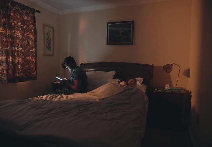 Timelapse of a man and woman spending time on their phones in bed at night