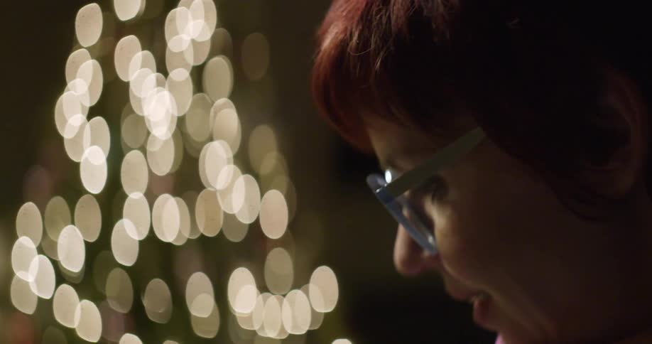 A woman smiles standing by a christmas tree