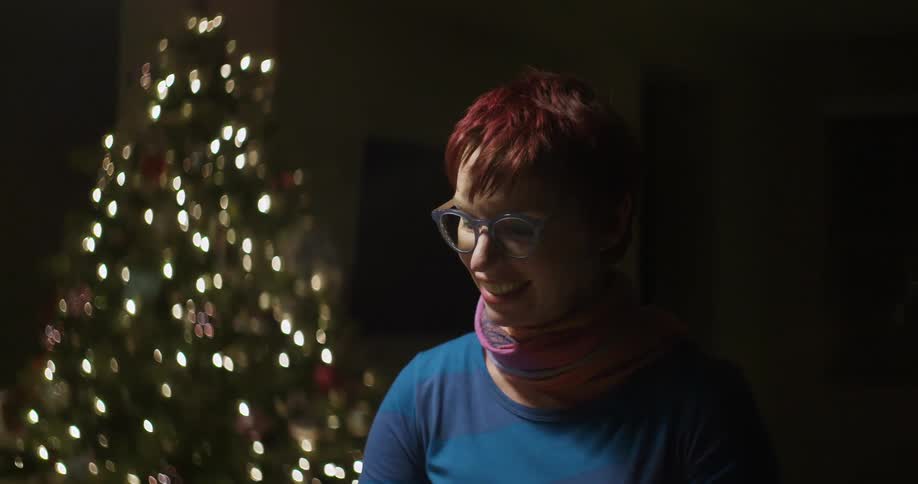 Man smiles with a christmas tree behind her
