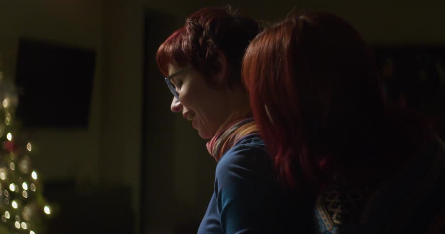 One woman hugs another as they interact in a home