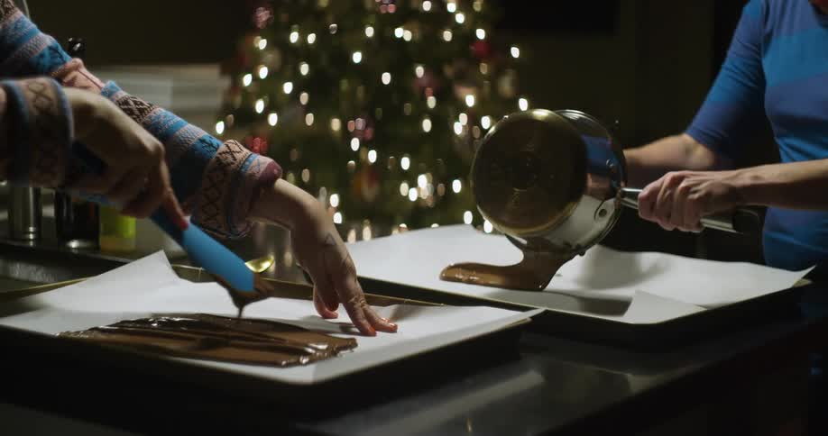Chocolate is poured into pans with a christmas tree in the background