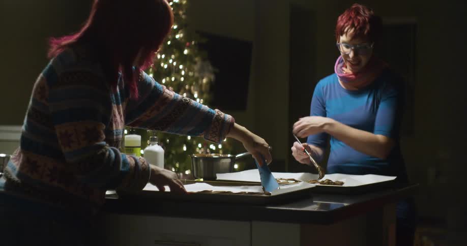 Two women are spreading chocolate into pans