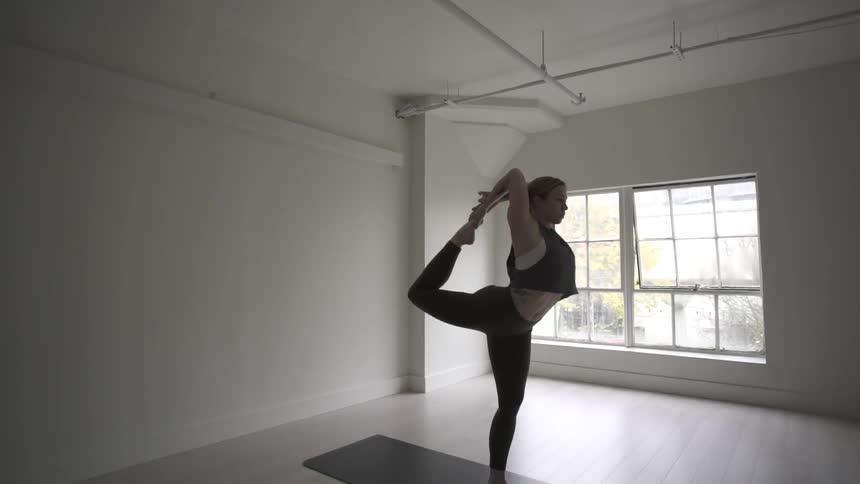 A woman stretches in an empty white room