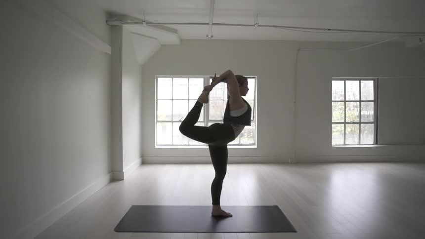 A woman is doing yoga in a large room