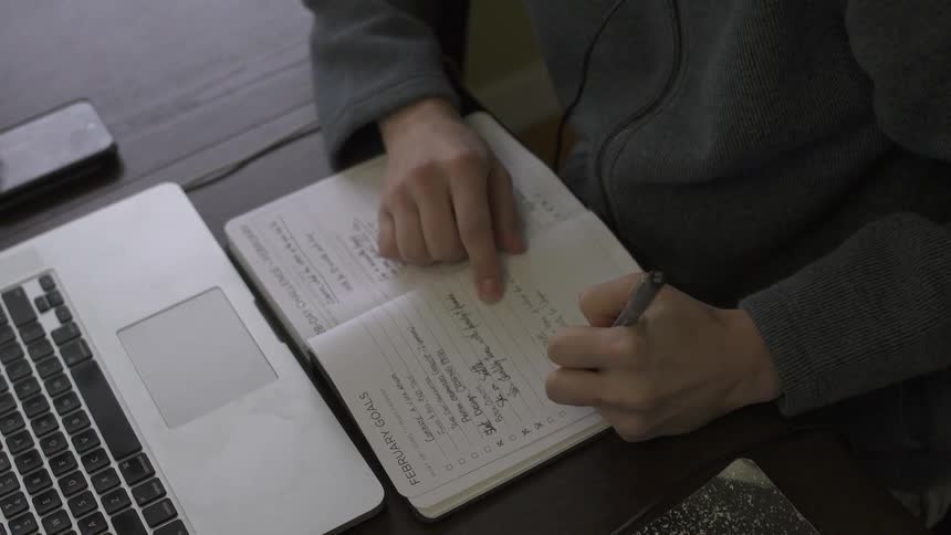 A man is working writing in a book
