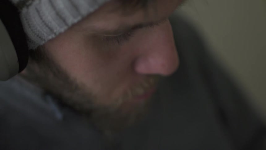 A man wearing a hat is looking down
